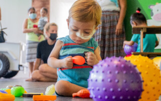 Blonde toddler pediatric patient playing with colored balls sensory toys