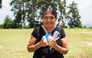 Guatemalan Woman holding toothbrush, har brush, toothpaste, hygiene items